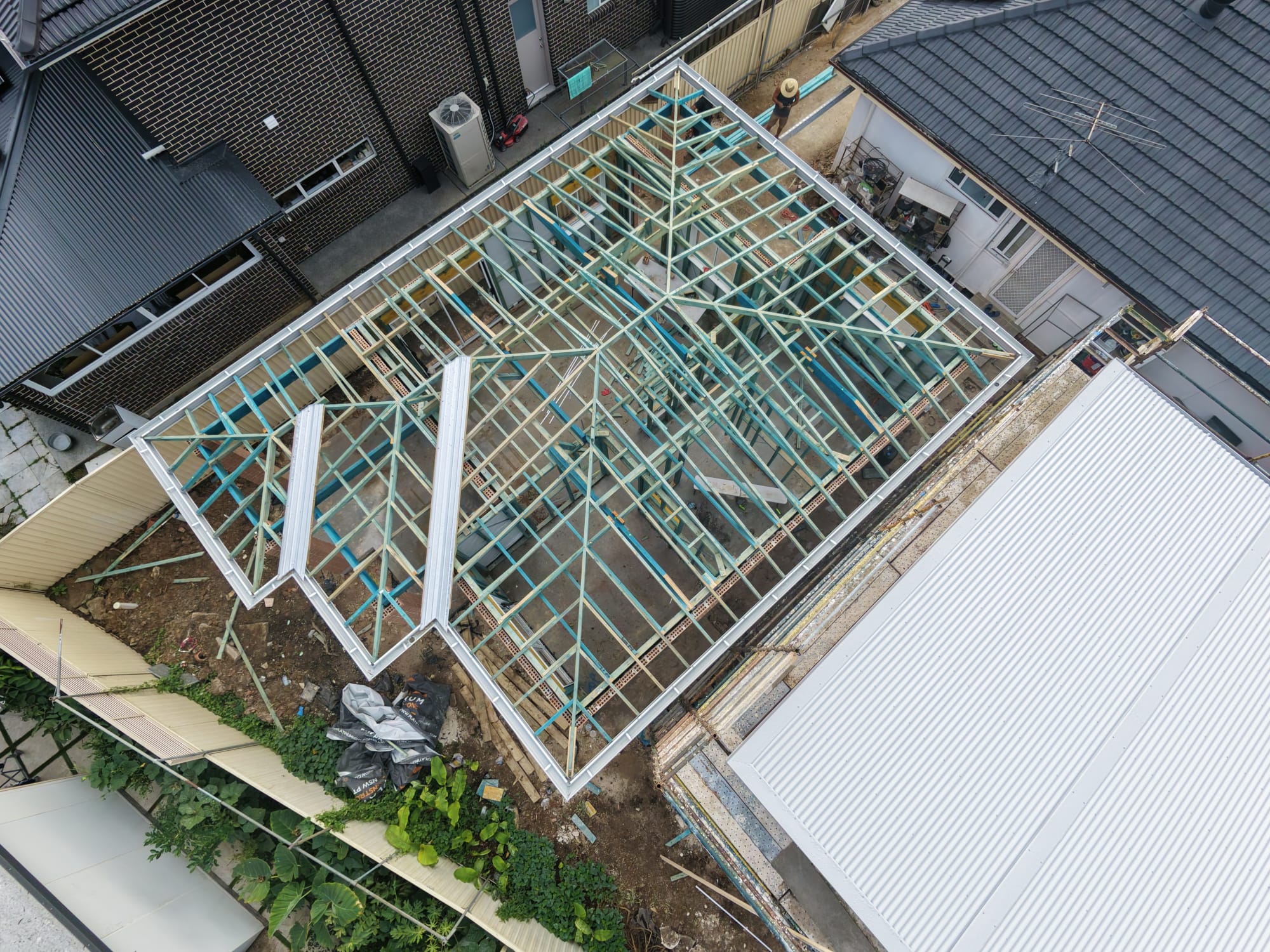 Top-down aerial view of a completed hip roof timber frame with steel fascia