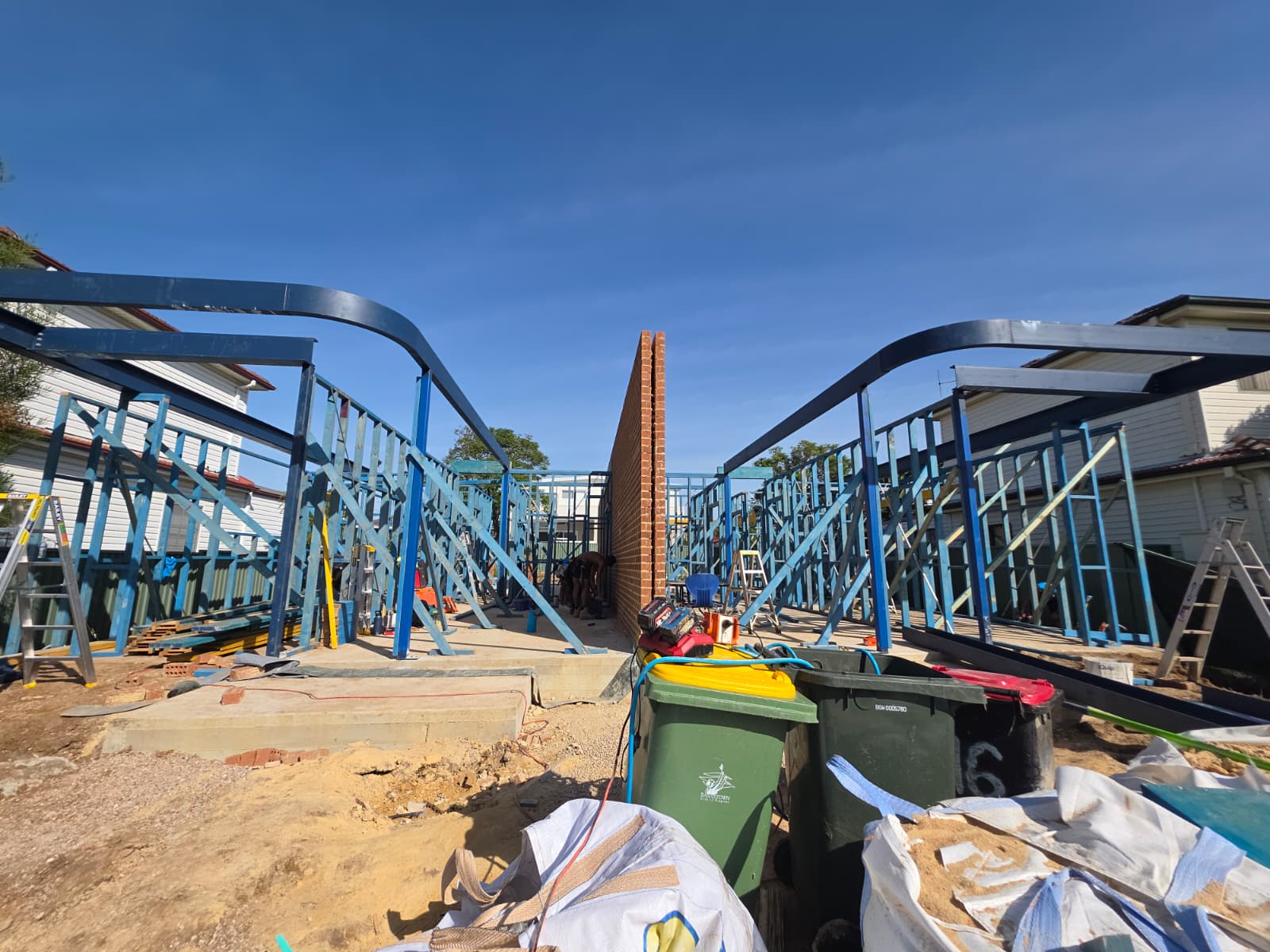 Structural steel portal beams spanning two framed additions either side of a brick wall