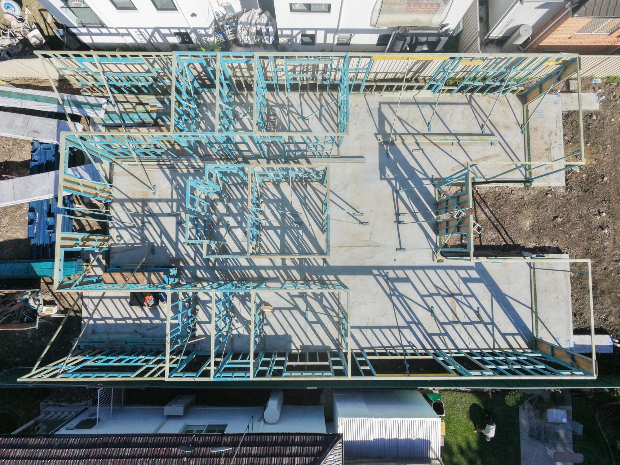 Top-down aerial view of timber wall frames set out across a concrete slab