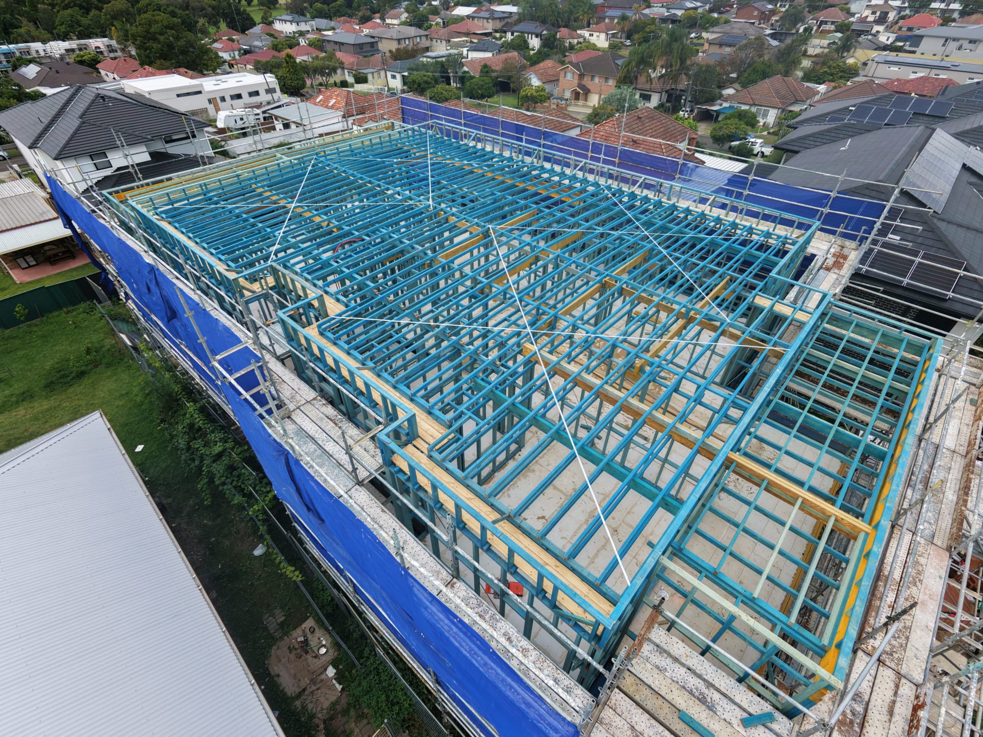 Aerial view of a two-storey timber frame with floor joists and scaffolding in place
